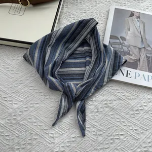 Close-up of blue and grey striped cotton scarf folded on a minimalist flat lay background