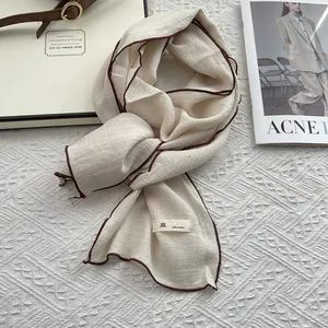 Minimalist linen scarf in beige with brown contrast edges and natural fabric texture