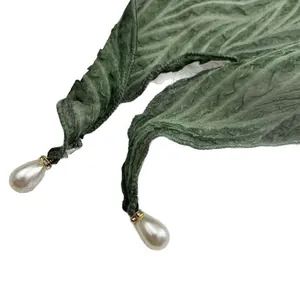 Elegante donkergroene geplooide sjaal met gouden ring en grote parelhanger als detail