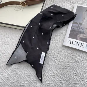 Detail shot of black polka dot linen skinny scarf with fine stitched edge and material label