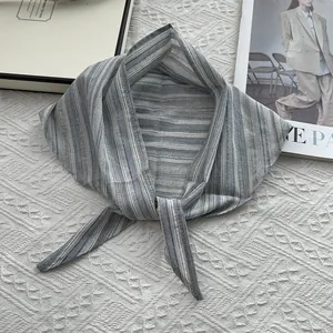 Detail of grey and blue striped cotton triangle scarf with knot on textured fabric