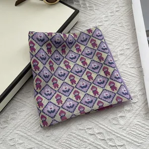 Detail eines lila Vintage-Halstuchs mit Rautenmuster, Cartoons und Blumenmotiven