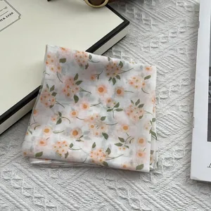 Detailed close-up of floral print silk scarf on lace background with orange flowers