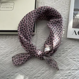Detailed view of pink paisley print satin silk scarf tied neatly on a white fabric