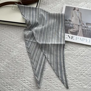 Detailed close-up of grey and blue striped cotton scarf on an elegant lace background