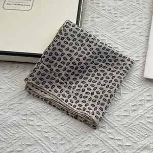 Close-up of a 55cm printed square scarf with black paisley pattern and fine edge stitching