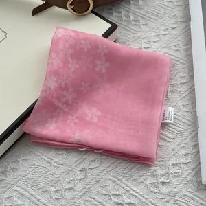 Detailed view of pink floral silk scarf showing material tag and fine edge stitching