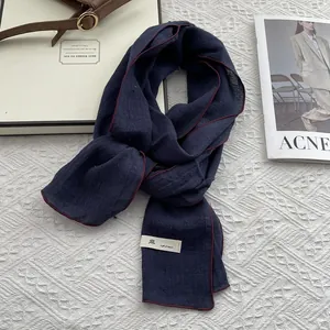 Detail of navy linen scarf with red contrast stitching and minimalist fabric label