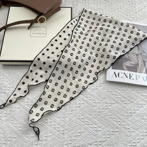 Polka dot cotton linen scarf accessory styled on a textured white surface with a handbag