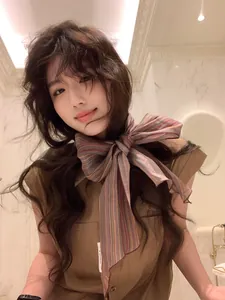 Detail of a colorful striped linen scarf tied in a bow on a sleeveless brown shirt