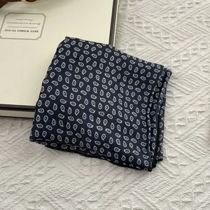 Macro detail of navy blue paisley silk scarf showing fine edge stitching and fabric texture