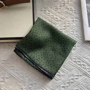 Detail of forest green cotton pocket square with black diamond pattern and rolled edges