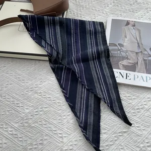 Detail shot of navy striped cotton triangle scarf on a white textured background