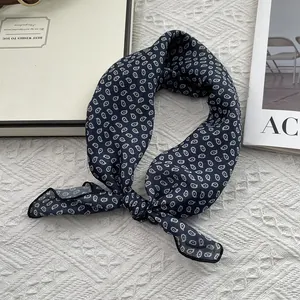 Detail of navy blue teardrop paisley scarf knotted on luxury gift box and magazine