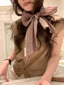 Detailed view of linen striped scarf tied in a large bow on model with fabric label