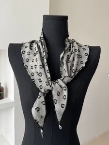 Detail of grey polka dot linen scarf with wavy edge on a display mannequin