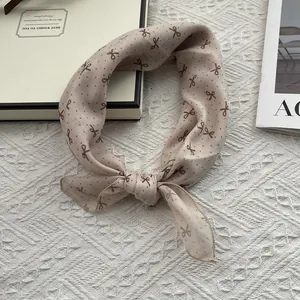 Detail of beige cotton linen scarf with polka dots and bow pattern on a quilted background