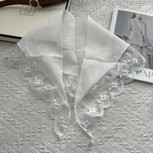 White lace triangle scarf with floral embroidery displayed on a stylish magazine background