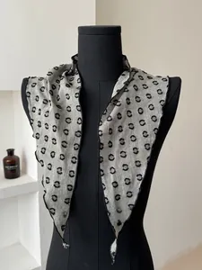 Close-up of light grey cotton linen scarf with black polka dots and hemmed edges