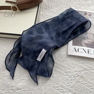 Detail of navy blue linen skinny scarf with fabric label on textured knit background