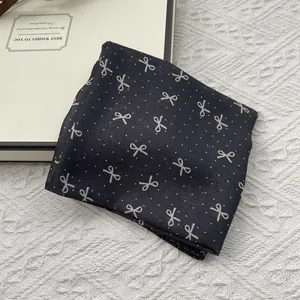 Polka dot bow pattern linen cotton neck scarf folded on a decorative book base