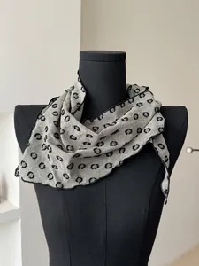 Detail of grey polka dot cotton linen scarf with elegant black wavy stitched edges on a model