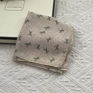 Elegant polka dot bow scarf in light pink cotton linen displayed in a gift box