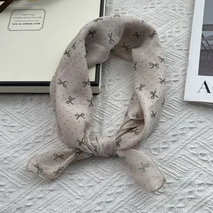 Detail of apricot cotton linen scarf with green bow pattern on white lace background