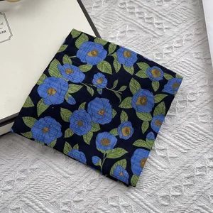 Detail van een vierkante katoenen linnen sjaal met blauwe camelia-bloemen op een matje