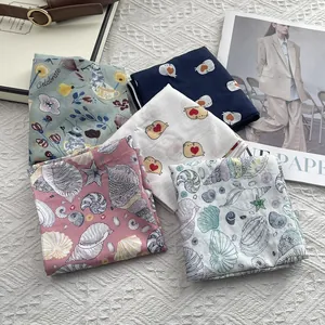 Flat lay of cotton square scarves with floral, cat, and shell prints in assorted colors