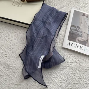 Chic blue and purple striped linen scarf displayed on a minimalist white textured surface