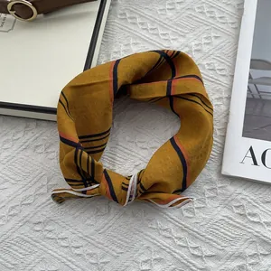 Détail d'un foulard en coton à carreaux jaune moutarde avec passepoil blanc sur tricot