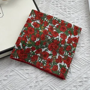 Detailopname van vierkante zijden sjaal met rode bloemenprint en rode rolzoom