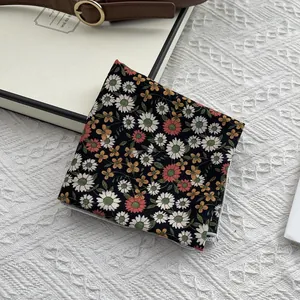 Gros plan du foulard carré en coton noir à fleurs avec marguerites et ceinture en cuir
