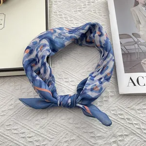 Detail of blue and orange patterned silk scarf styled as a headband on knit background