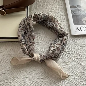 Beige paisley silk scarf with green and brown patterns tied in a stylish knot