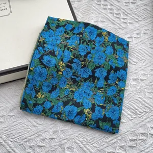 Detail van een zijden sjaal met bloemen op witte textuur met een geschenkdoos
