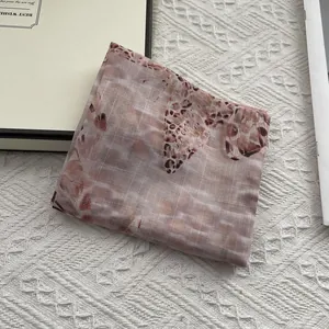 Detail of translucent checkered cotton-linen scarf with abstract brown print and fine stitching