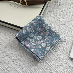 Gros plan d'un foulard carré en coton à fleurs bleu clair avec imprimé marguerite