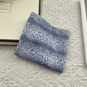 Detailed macro texture of blue and brown speckled cotton linen square scarf on knit background