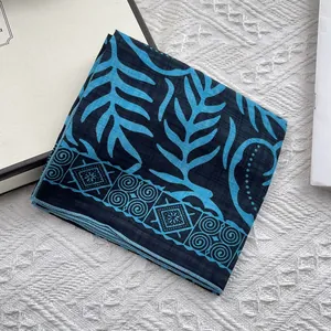 Close-up of floral cotton linen scarf with blue leaf patterns and vintage geometric border