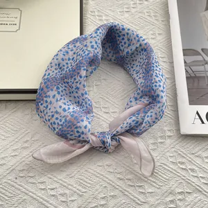 Detail of silk-texture neck scarf with blue and pink leopard print tied in a knot