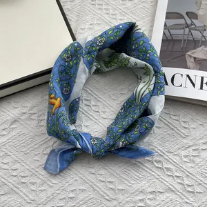 Detail of floral and bird print scarf on white knit background with a fashion magazine