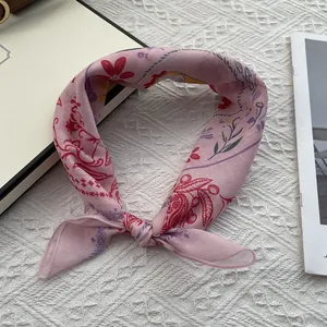 Pink floral cotton linen square scarf tied in a bow on a cozy beige background
