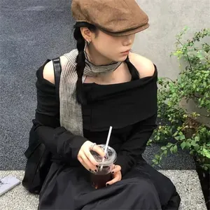 Detail showing elegant black off-shoulder knit top with striped shawl in street style