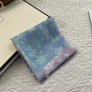 Detailed view of folded floral cotton linen scarf featuring blue and purple petal prints
