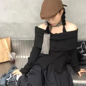 Detail of artistic checkered linen scarf styled with a casual black off-shoulder knit top