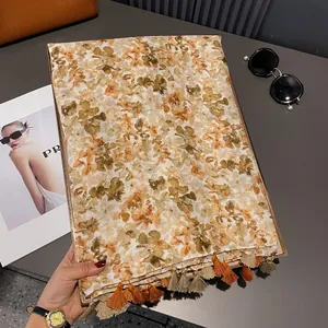 Close-up of lightweight floral scarf featuring orange tassels and vintage patterns