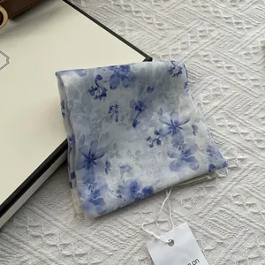 Detail of light blue floral print on white sheer linen scarf with delicate rolled edges