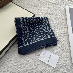 Close-up of navy blue paisley cotton scarf with star patterns and gift box detail